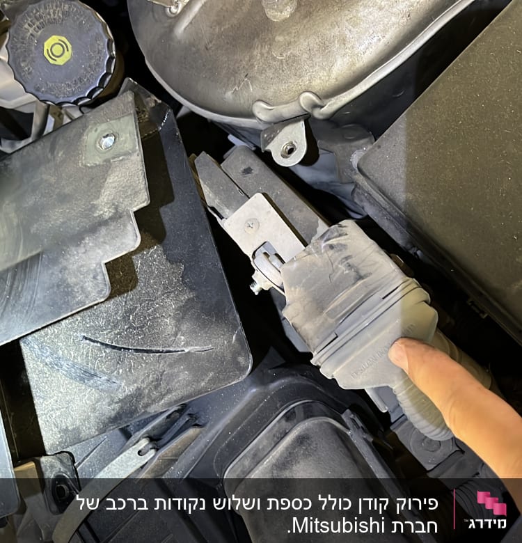 יד מצביעה על חלק במנוע רכב עם מכסה פלסטיק